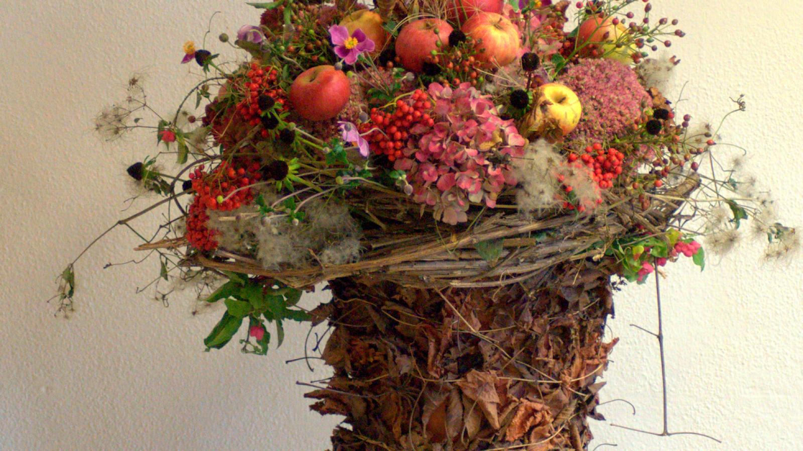 Gefäss mit Blättern und gefüllt mit Herbstblumen 